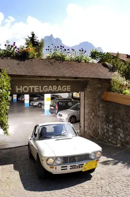 a white car parked in front of a hotel garage at Parc Hotel Tyrol in Castelrotto