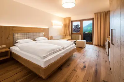 a bedroom with a large bed and a large window at Hotel Der Waldhof in Vollan