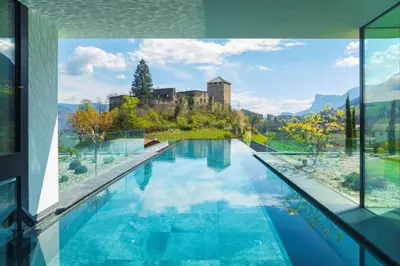 a house with a swimming pool with a castle in the background at Hotel Der Waldhof in Vollan