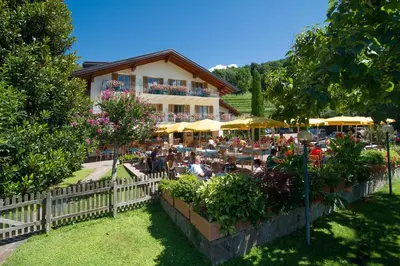 a restaurant with people sitting at tables in front of a building at PENSION KLUGHAMMER in Caldaro