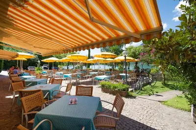 an outdoor restaurant with tables and chairs with umbrellas at PENSION KLUGHAMMER in Caldaro
