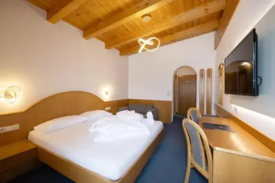 a bedroom with a bed and a desk and a tv at PENSION KLUGHAMMER in Caldaro