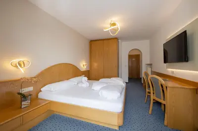 a hotel room with a bed and a flat screen tv at PENSION KLUGHAMMER in Caldaro