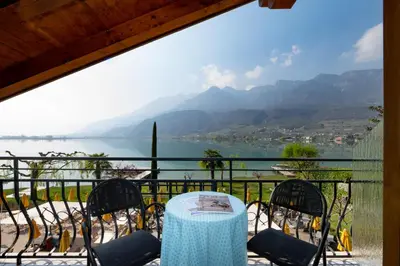 a table and chairs on a balcony with a view of the water at PENSION KLUGHAMMER in Caldaro
