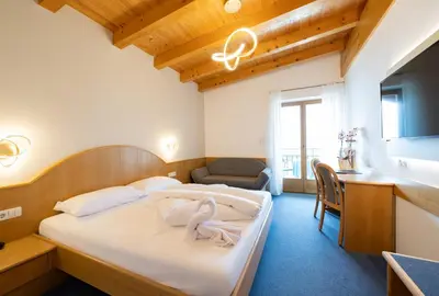 a bedroom with a bed and a desk and a chair at PENSION KLUGHAMMER in Caldaro
