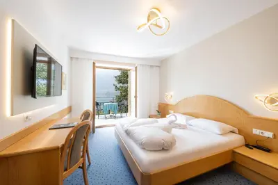 a hotel room with a bed and a desk and a window at PENSION KLUGHAMMER in Caldaro