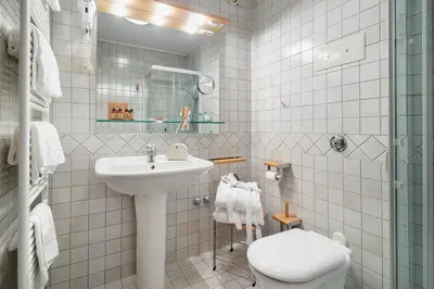 a white bathroom with a sink and a toilet at Hotel Cristallino d'Ampezzo in Cortina dʼAmpezzo