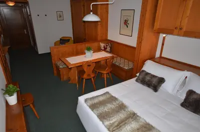 a room with a bed and a table and a tableablish at Hotel Cristallino d'Ampezzo in Cortina dʼAmpezzo
