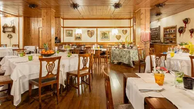 a restaurant with tables and chairs with white tablecloths at Hotel Cristallino d'Ampezzo in Cortina dʼAmpezzo