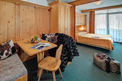 a living room with a table and a bed at Hotel Cristallino d'Ampezzo in Cortina dʼAmpezzo