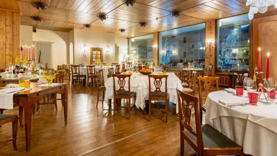 a restaurant with tables and chairs with white table cloth at Hotel Cristallino d'Ampezzo in Cortina dʼAmpezzo