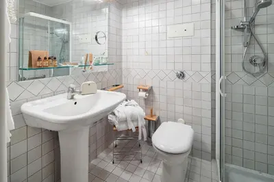 a white bathroom with a sink and a toilet at Hotel Cristallino d'Ampezzo in Cortina dʼAmpezzo