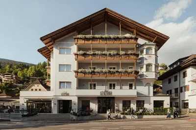 a tall white building on a city street at Hotel Genziana in Ortisei