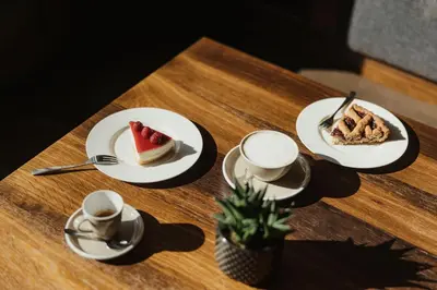 a table with plates of cake and cups of coffee at Hotel Genziana in Ortisei