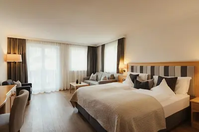 a hotel room with a large bed and a couch at Hotel Genziana in Ortisei