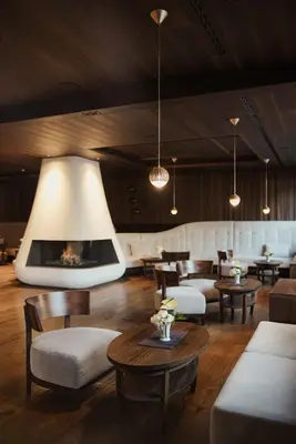 a lobby with couches and tables and a fireplace at Hotel Genziana in Ortisei