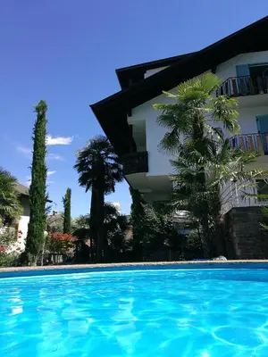 a swimming pool in front of a building with palm trees at Residence Reinhild in Nalles