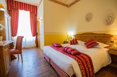 a bedroom with a large bed with red pillows on it at Hotel Villa Imperina in Agordo