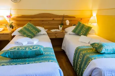 two beds with green and blue pillows in a room at Hotel Villa Imperina in Agordo