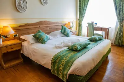 a bedroom with a large bed with pillows on it at Hotel Villa Imperina in Agordo