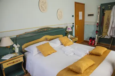 a bedroom with a large white bed with yellow pillows at Hotel Villa Imperina in Agordo