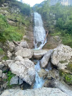 a waterfall on the side of a hill with rocks at Piccolo Nido Falcade in Falcade