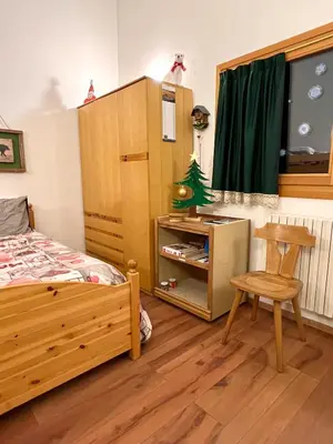 a bedroom with a bed and a table and a chair at Piccolo Nido Falcade in Falcade
