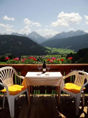 a table and chairs on a deck with a view of mountains at Hochwieserhof in Monguelfo
