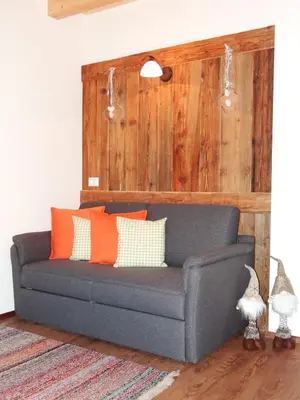 a gray couch with orange pillows in a living room at Hochwieserhof in Monguelfo