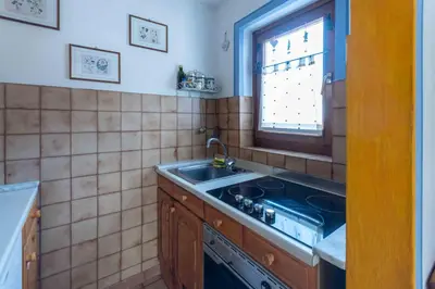 a kitchen with a stove and a sink and a window at Casa Riccardo in Soraga