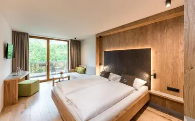 a bedroom with a large bed and a large window at Hotel Birkenbrunn in Naz-Sciaves