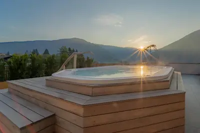 a hot tub on the roof of a house with the sunset at Hotel Birkenbrunn in Naz-Sciaves