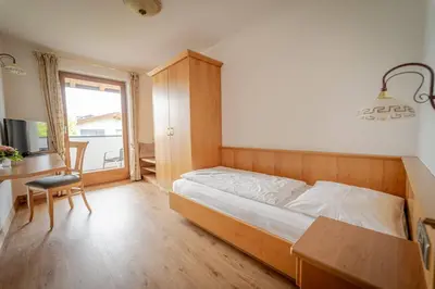 a bedroom with a bed and a desk and a window at Hotel Birkenbrunn in Naz-Sciaves