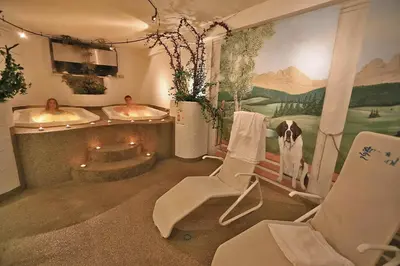 a bathroom with two sinks and a chair and a bath tub at Hotel Vigo in Vigo di Fassa