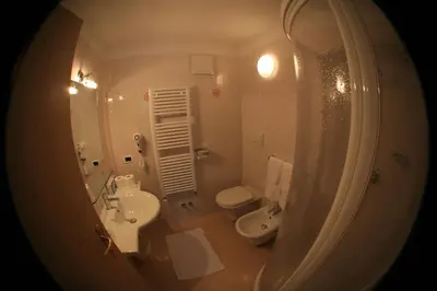 a bathroom with a sink and a toilet and a mirror at Hotel Vigo in Vigo di Fassa