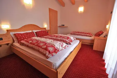 a bedroom with two beds with red and white covers at Hotel Vigo in Vigo di Fassa