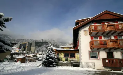 a building with snow on the ground in front of it at Hotel Vigo in Vigo di Fassa