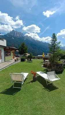two lounge chairs sitting on top of a field of grass at Hotel Vigo in Vigo di Fassa