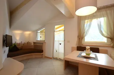 a small living room with a table and a window at Mason La Zondra in Vigo di Fassa