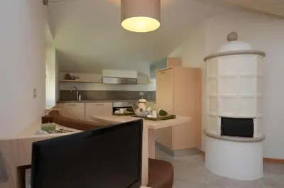 a living room with a television and a kitchen at Mason La Zondra in Vigo di Fassa