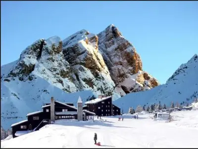 a building in the snow with a mountain at Casa Ciotoli in Falcade
