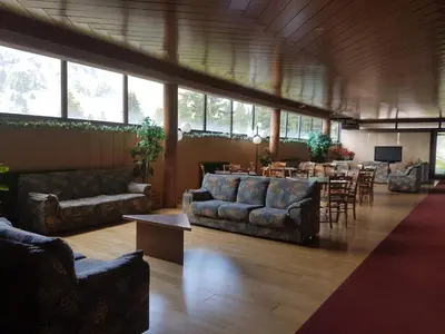 a living room with couches and a table and chairs at Casa Ciotoli in Falcade