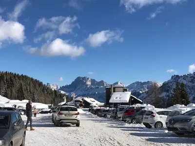 a parking lot with cars parked in the snow at Casa Ciotoli in Falcade