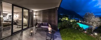 a room with a balcony with a bed and a pool at Mair Am Ort Living Hotel B&B in Parcines
