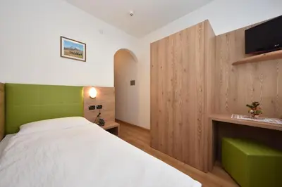 a bedroom with a bed and a tv on a wall at Villa Gemmy in Pozza di Fassa