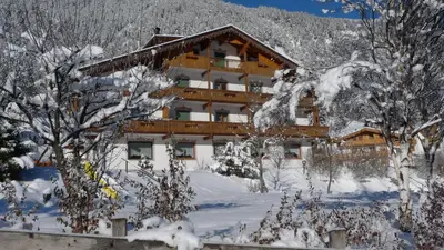 a building covered in snow with trees in front of it at Villa Gemmy in Pozza di Fassa