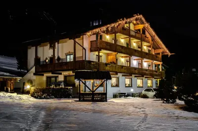a large building in the snow at night at Villa Gemmy in Pozza di Fassa