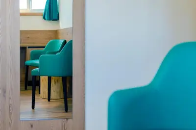 a mirror reflecting a row of green chairs in a room at Villa Gemmy in Pozza di Fassa