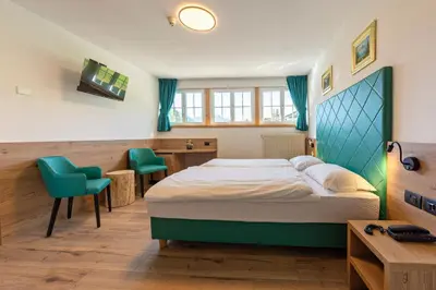 a bedroom with a bed and two green chairs at Villa Gemmy in Pozza di Fassa