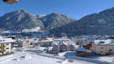 a town covered in snow with mountains in the background at Villa Gemmy in Pozza di Fassa
